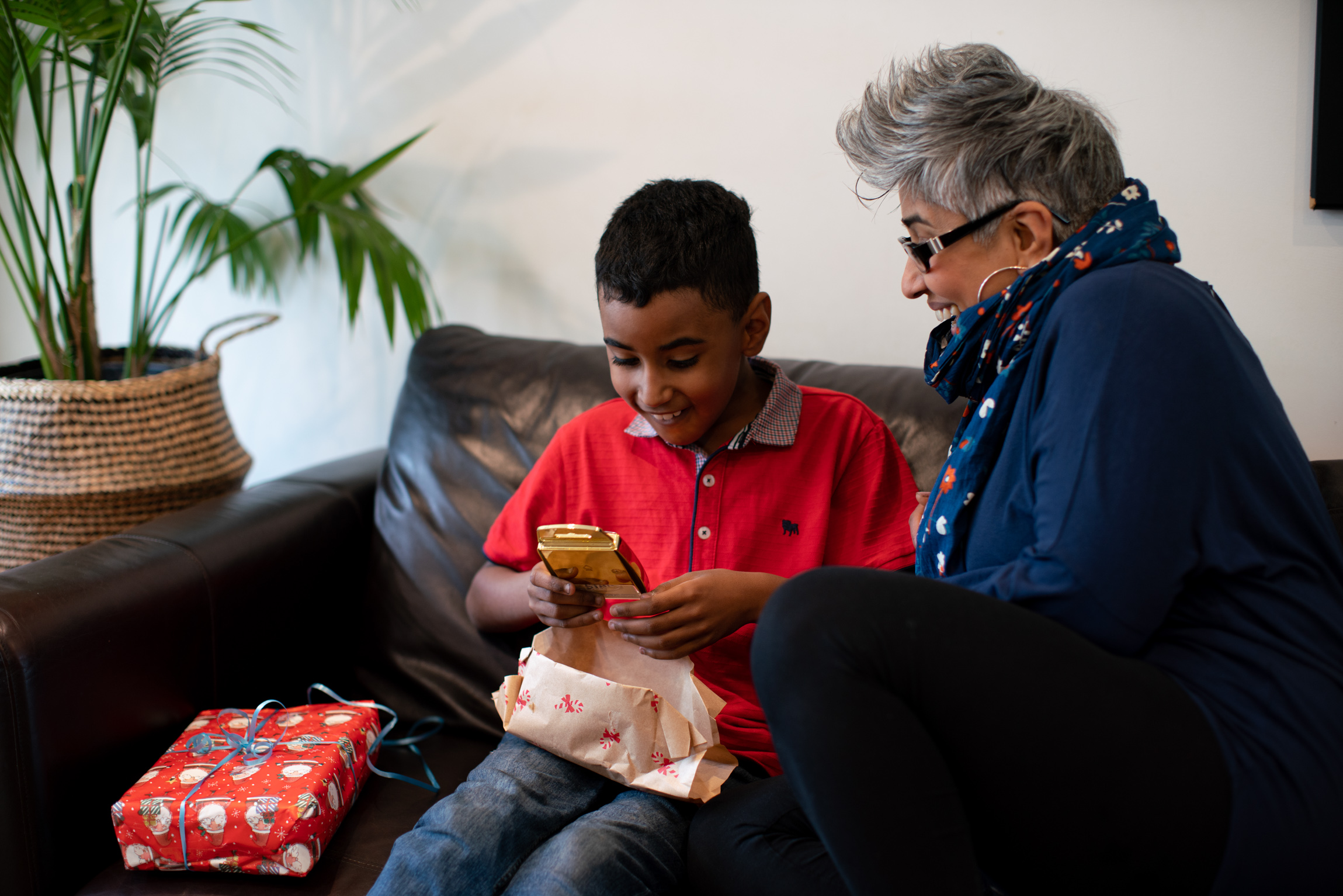 Child opening Christmas present with a woman.