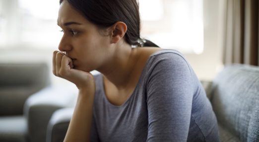 A women sits at home looking contemplative