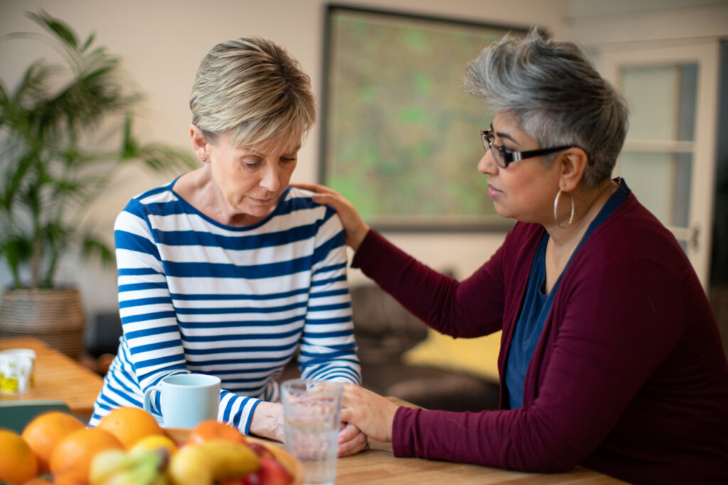 One women comforts another in a home setting