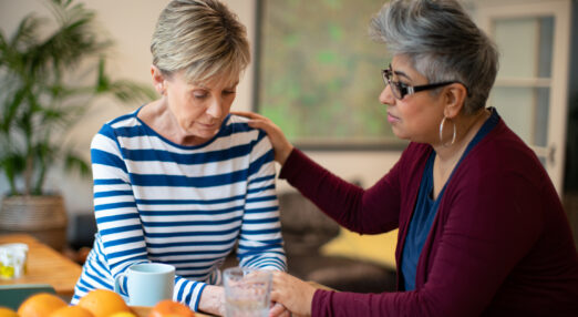 One women comforts another in a home setting