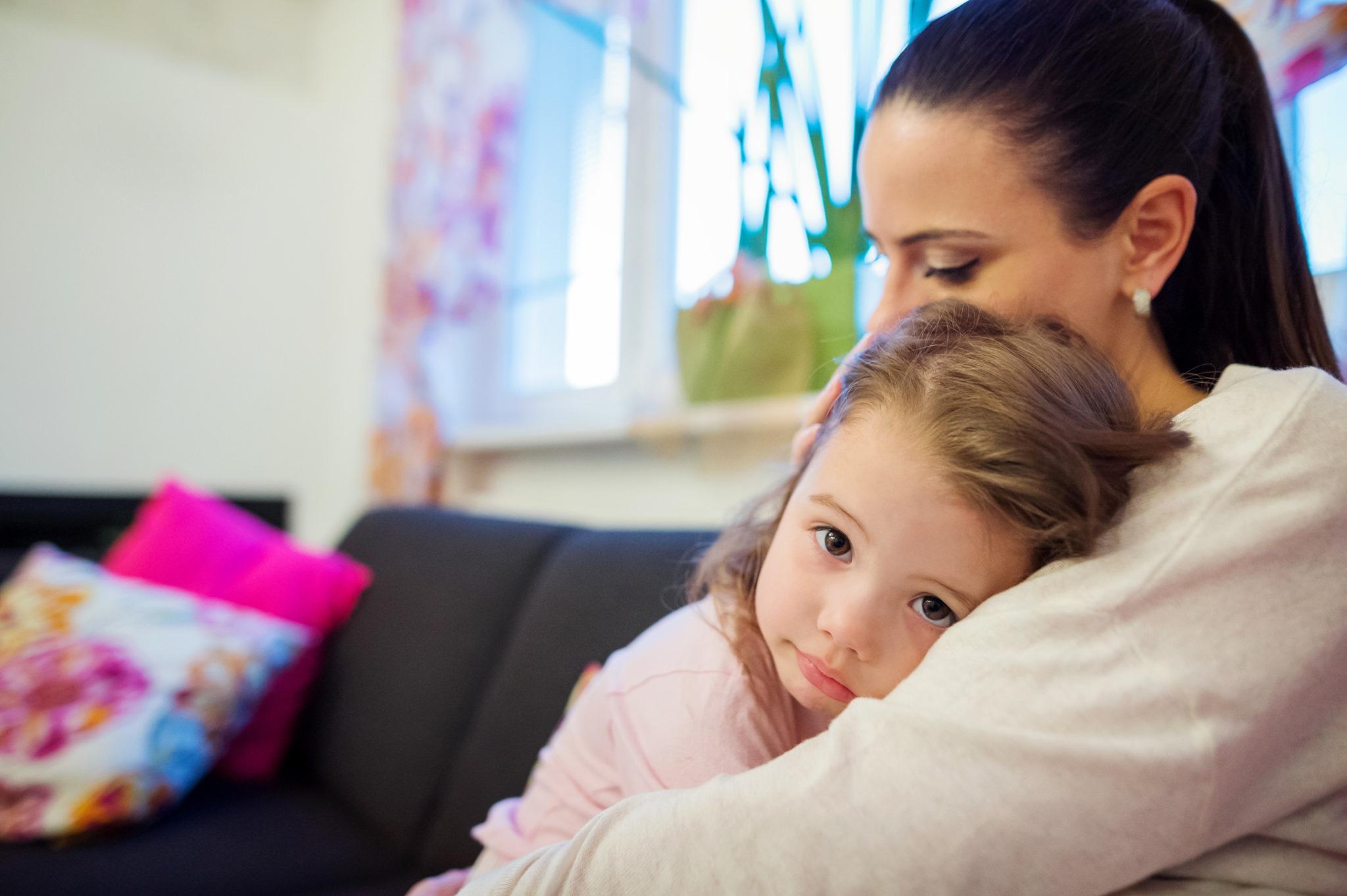 A mother and child sit on a sofa.