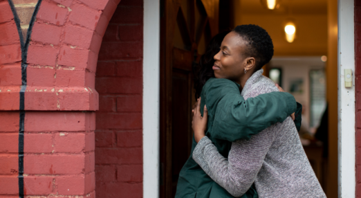 Two women hug in a doorway